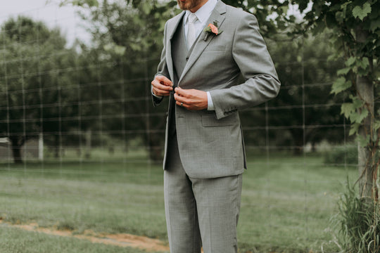 Man wearing wedding ring buttoning his suit jacket - Photo Credit: Samantha Gades/Unsplash
