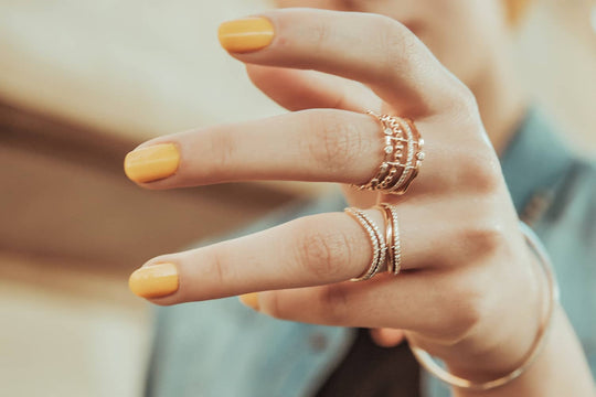 Woman wearing stackable rings with yellow nails - Photo Credit: Sour Moha/Unsplash